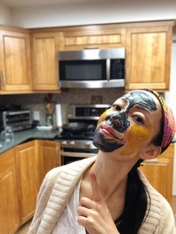 A woman in the kitchen with colorful facial mask