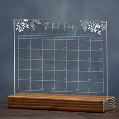 an acrylic sign with wooden base that's printed with a calendar and floral header