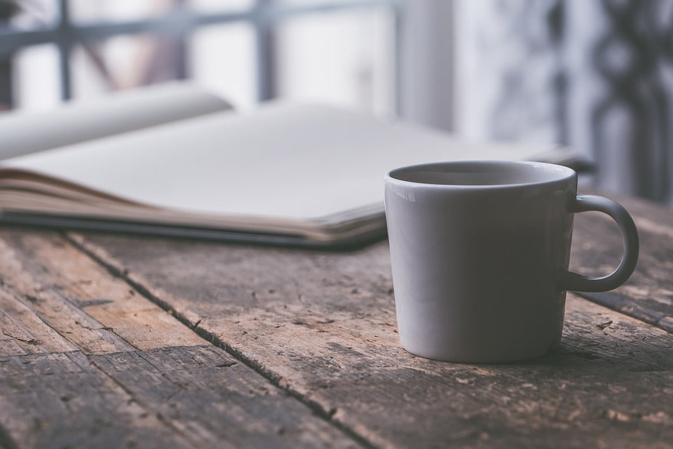 A daily planner and coffee cup on a rustic wooden table.