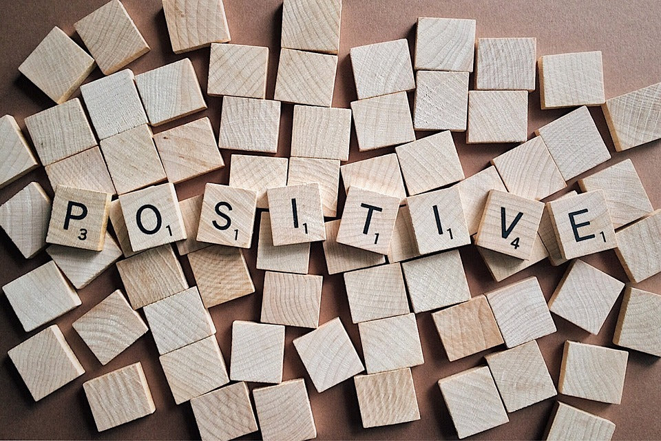 The word positive spelled out using wooden scrabble block letters.