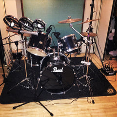 Drum set inside of a recording studio with Microphones set up