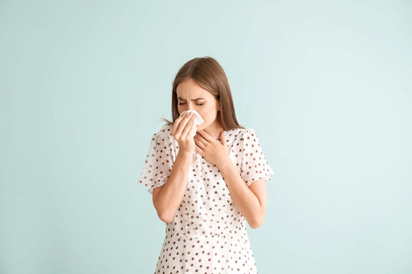 Donna con allergia da inalazione si soffia il naso