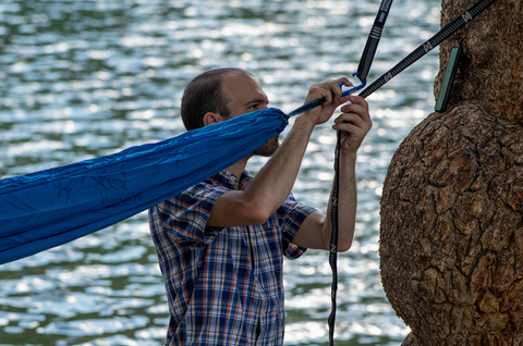 A man hanging a CordaRoy's Travel Ripstop Hammock on a tree. 