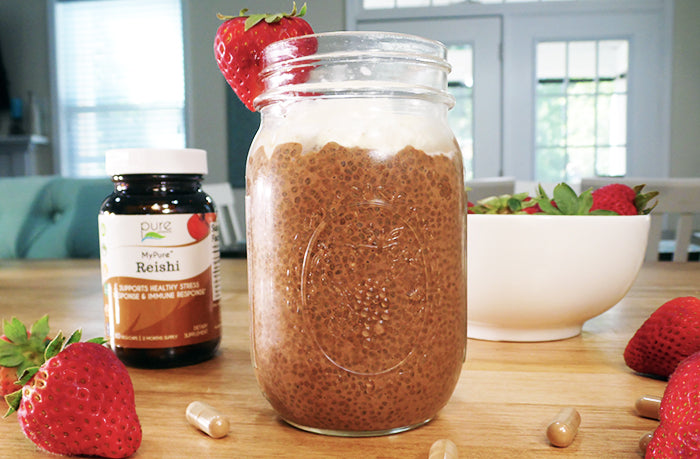 Chocolate Chia Reishi Pudding on countertop with strawberries and a bottle of MyPure Reishi