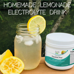 Mason jar glass filled with lemonade, next to a small tub of Ionic-Fizz Calcium Plus supplement and fresh squeezed lemons.