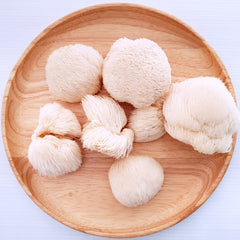 Fluffs of Lion's Mane mushrooms displayed on wooden tray