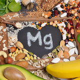 foods rich in magnesium (avocado, banana, spinach, seeds, and nuts) poured around a heart that says Mg