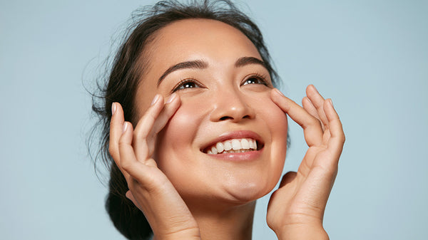 Happy woman applying eye cream