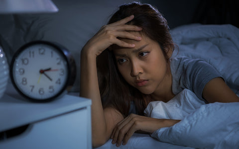 Woman staring at alarm clock in the middle of the night because she can't sleep.