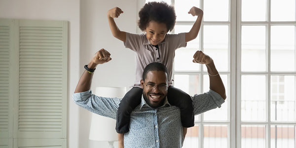 Dad with kid on shoulders showing off strong arms