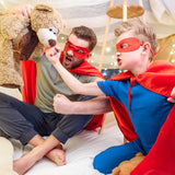 father and son play-pretend superheroes inside a blanket fort