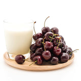 Cup of milk on a platter with a pile of cherries - both are food with melatonin