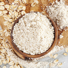 bowl of oat flour surrounded by oat grain