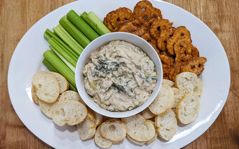 platter of celery, bread, and pretzels around bowl of MYcoMUne Hot Spinach Artichoke Dip