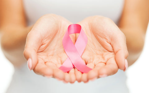 close up of hands holding a pink awareness ribbon for Breast Cancer Awareness