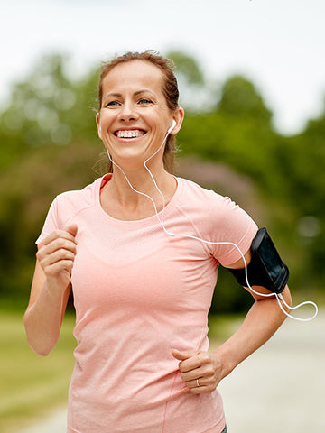 Mature woman enjoys a jog outdoors while listening to music through headphones