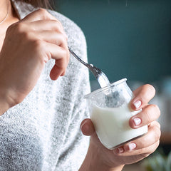 up close on woman's hands scooping a bite of yogurt with spoon