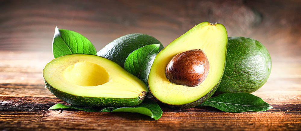 avocado sliced in half and displayed on wooden table top