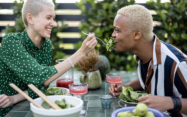 A couple enjoys a salad while eating outdoors