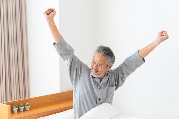 Man waking up and stretching in bed after a good night's sleep