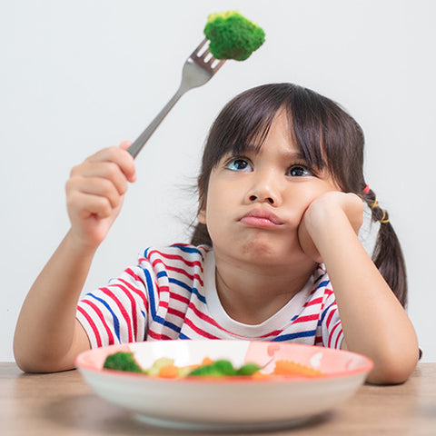 Young girl picky eater pouts at broccoli on her fork