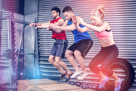 3 people jump onto raised platforms as part of physical training