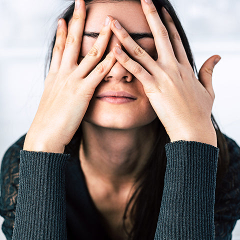 stressed out woman puts her head against her hands