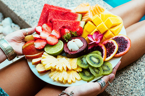 someone holds a plate of many different colored foods