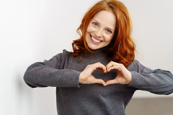 woman makes a heart with her hands in front of her chest