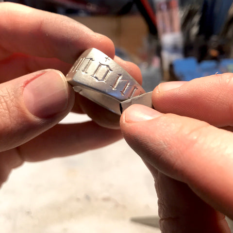 Silver signet ring being sanded with emery paper