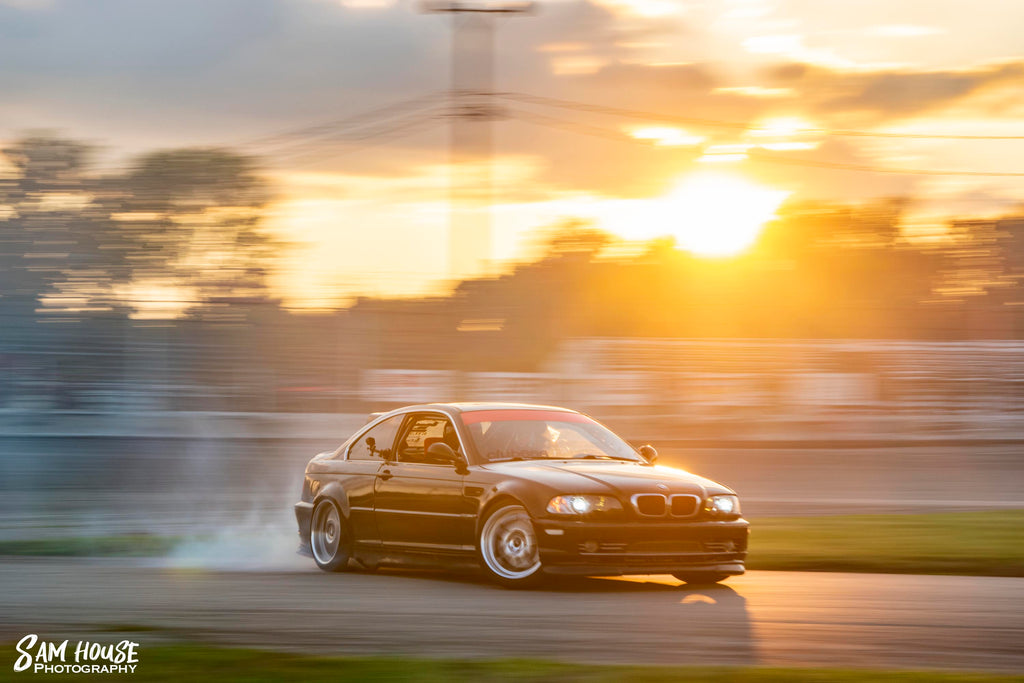 Black E46 coupe drifting at sunset