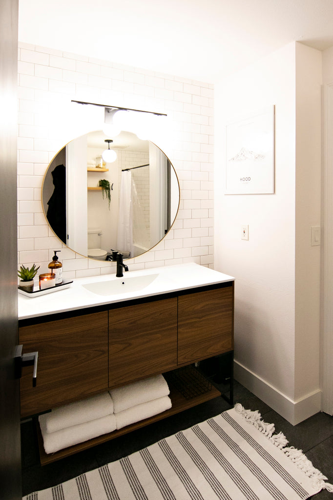 Modern bathroom remodel with round mirror and white subway tile wall