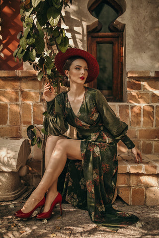 La blogueuse Aida Đapo Muharemović portant notre emblématique robe portefeuille verte, Verdant. Agencer avec un chapeau à larges bords et des talons rouges assortis.
