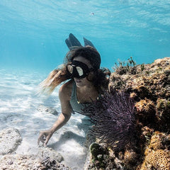 Martina Alvarez freediving in a coral reef wearing VANDAYA gold shark tooth necklace.