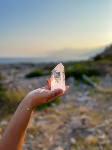 clear quartz tower point in hand with sea background