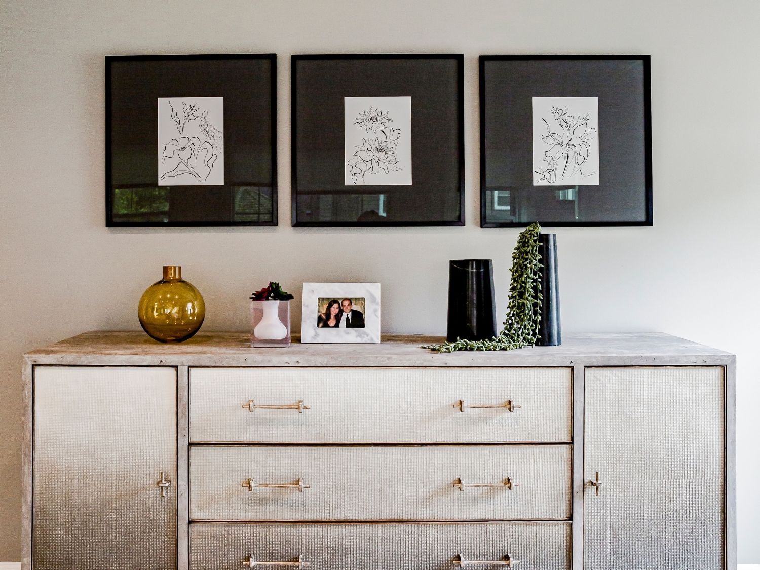 Three pieces of custom artwork above a bedroom dresser