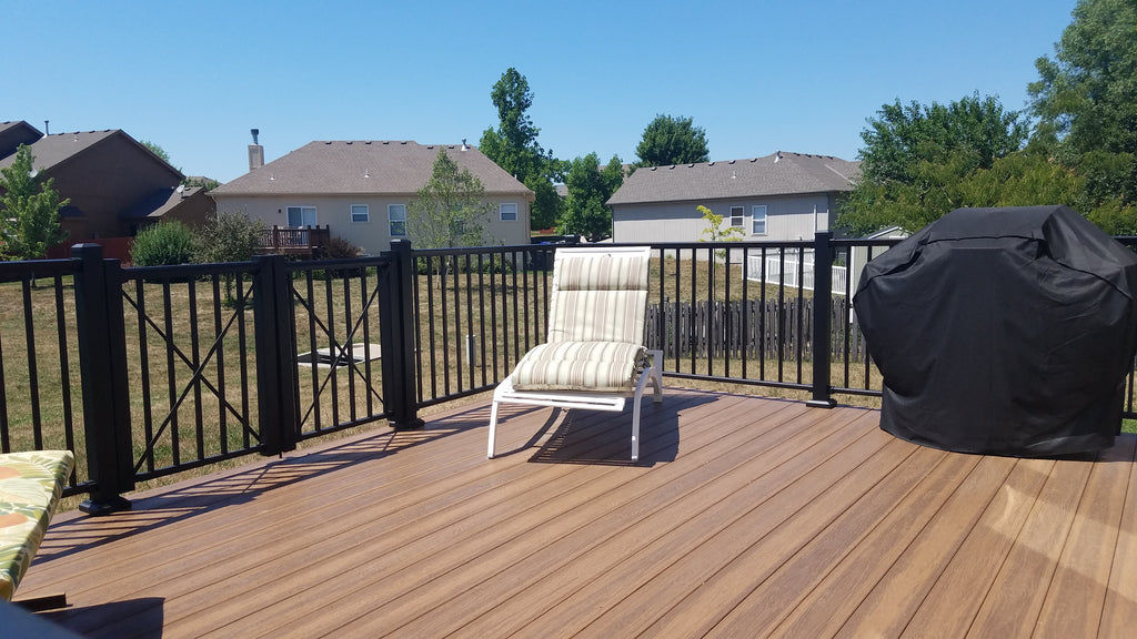 DekPro Prestige Rail behind a chair and a grill atop envisions tangled twine decking. gate on the left side with a blue sky