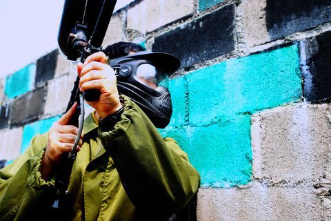 Paintball player hiding behind a wall
