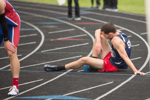 Exhausted track athlete, sitting on track 