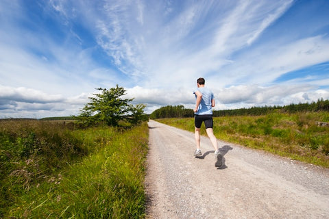 Male runner on gravel road, blue skies