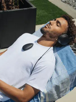 Man outside laying on lounger with sensate on his chest