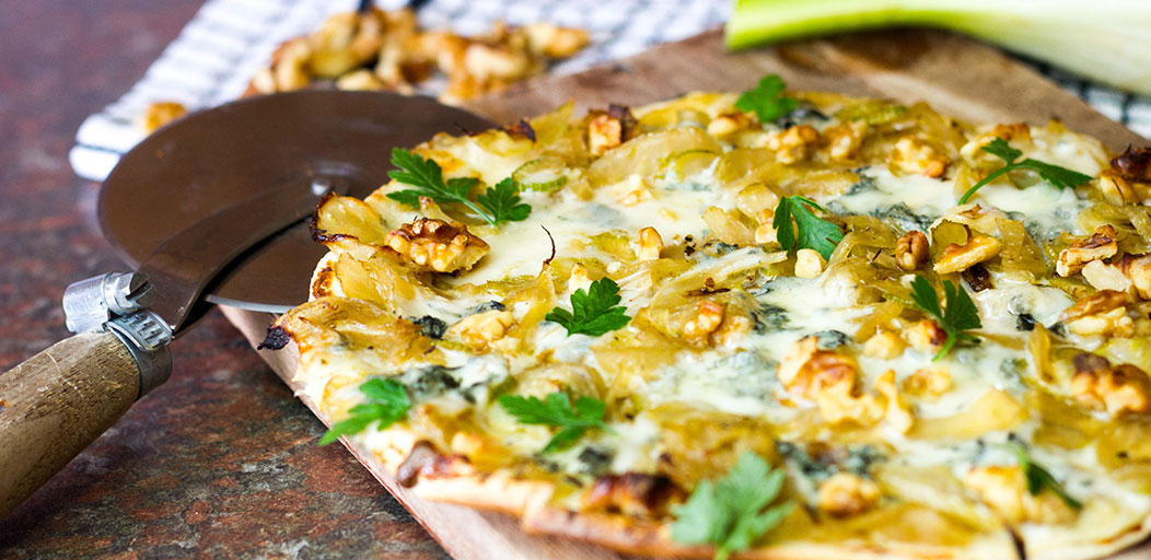 Low carb low cheese and fennel Lo-Dough pizza on a board with a pizza cutter