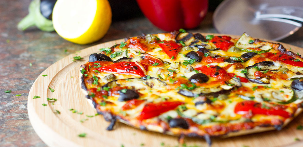 Low calorie Mediterranean vegetarian Lo-Dough pizza on a wooden board