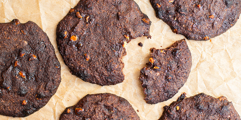 Lo-Dough double chocolate chip cookies on brown paper with a bite out 