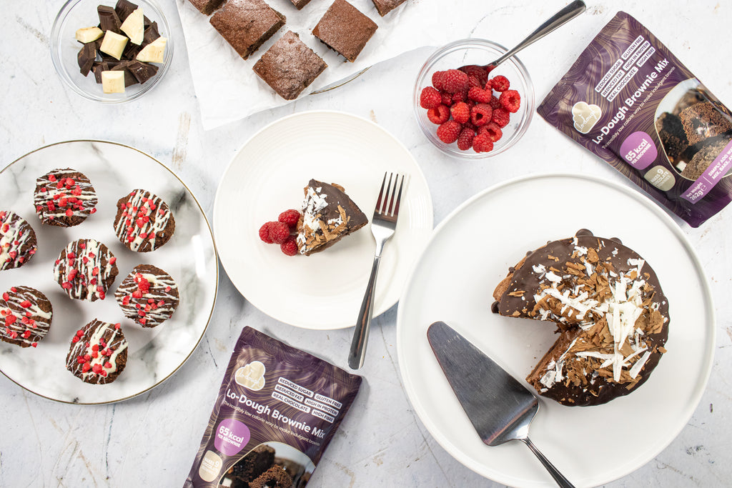 Low calorie brownie mixes on a table with cake, brownies and muffins