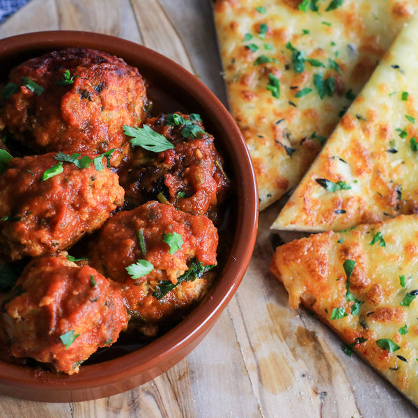 Low carb Spanish meatballs in a bowl with cheesy garlic bread