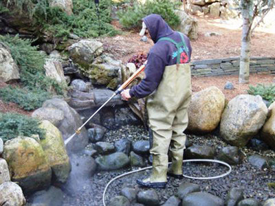 Pressure washing the pond and rocks in an annual spring pond cleaning