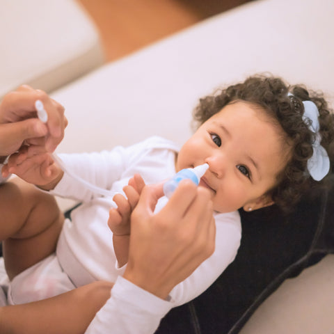 baby lying down with nasal aspirator in nose