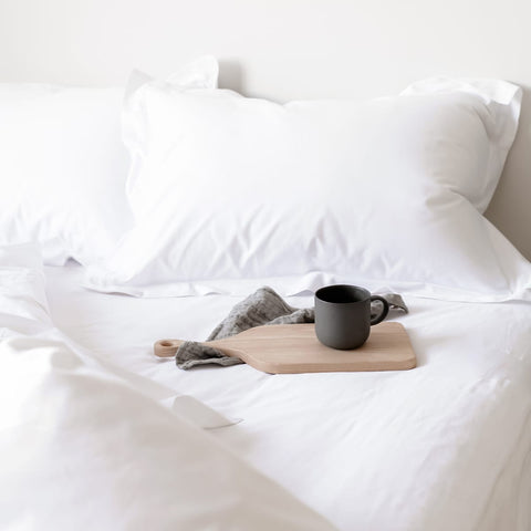 Egyptian cotton bedding on made bed with mug and tray