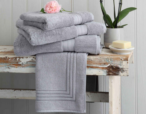 Grey bath towels on rustic bench with flower and accessories